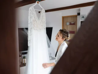 Fotograf Kamerzysta Weselny Lubuskim Przygotowania, Kinga spogląda na suknię ślubną